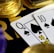 A close-up view of playing cards, specifically a Queen and a Ten of spades, surrounded by shiny gold coins and part of a poker chip, suggesting a gambling or casino theme.